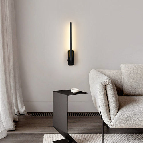 Rechargeable LED wall sconce mounted vertically beside a sofa, lit warm white