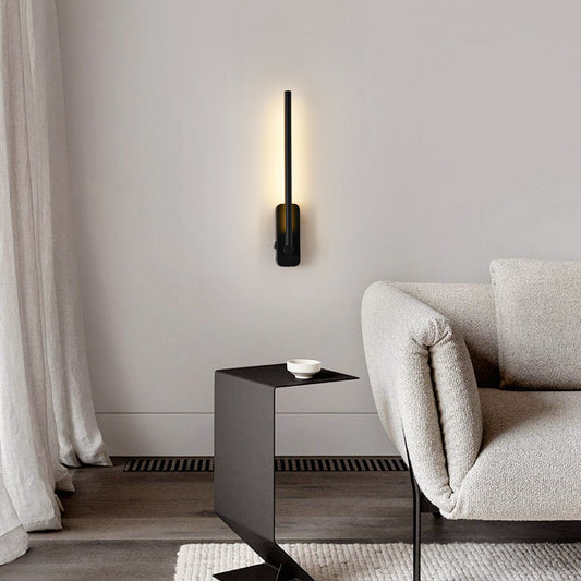 Rechargeable LED wall sconce mounted vertically beside a sofa, lit warm white